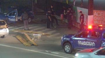 Madeiras e carrinho de supermercado jogados na avenida com viaturas da guarda no entorno. #paratodosverem