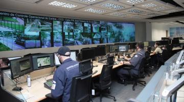 vista geral do Centro de Controle Operacional com homens trabalhando diante de um grande telão. #paratodosverem