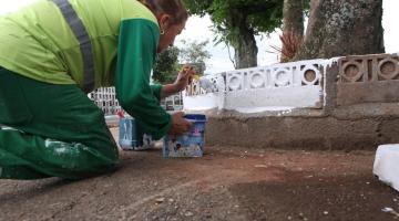 operária pintando guia em cemitério #paratodosverem