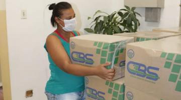 mulher pega cesta básica em pilha de caixas #paratodosverem  