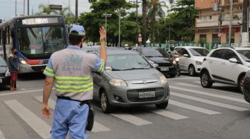 Agente está na pista, próximo a uma faixa de segurança. Ele sinalizada para carros em movimento. #Paratodosverem