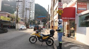 Agente da CET com a moto estacionada fiscaliza via. #paratodosverem