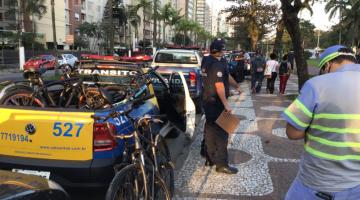 Carro com várias bicicletas em cima e ao lado agente da CET. #paratodosverem