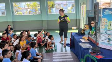 agente fala com alunos ao lado de teatro de fantoches #paratodosverem 