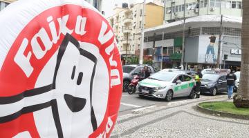 agente aborda taxi e no primeiro plano inflável da campanha #paratodosverem