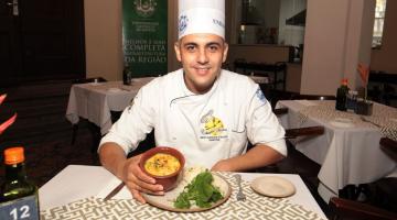 O chef Junior MOnteiro diante de um prato na mesa. #Paratodosverem