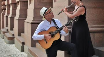 homem toca violão olhando para mulher #paratodosverem