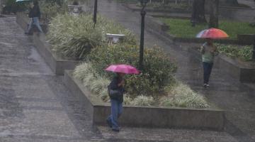 pessoas de guarda chuva em praça #paratodosverem