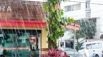 chuva caindo em rua. com estabelecimento comercial ao fundo e pessoas na rua. #paratodosverem