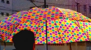 pessoa de costas está segurando guarda chuva ultra colorido em meio ao cenário cinzento e chuvoso. #pratodosverem