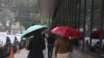pessoas andando de guarda chuva #paratodosverem 