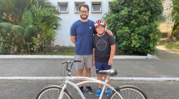 Pai e filho posam na frente da bicicleta. #Paratodosverem