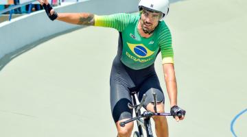 atleta sobre bicicleta com capacete , com braço direito esticado #paratodosverem