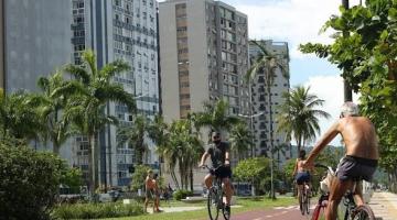 Ciclistas pedalam em ciclovia na Ponta da Praia. #pracegover