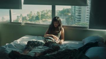 em cena de filme,  mulher está em cama, encostada em janela #paratodosverem