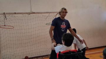 criança em cadeira de rodas brinca com instrutor. #paratodosverem
