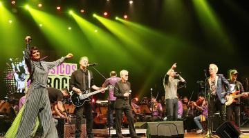 cantores estão no palco com orquestra sinfônica ao fundo. #paratodosverem