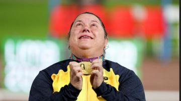 Beth Gomes segura medalha com as duas mãos à frente do peito. Ele olha para o alto. #Pracegover