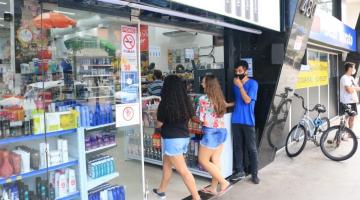 duas mulheres de costas entrando em loja. Ja porta, há também um homem de máscara. #paratodosverem