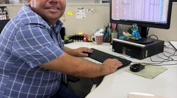 Servidor olha para a câmera sentado no computador #paratodosverem 