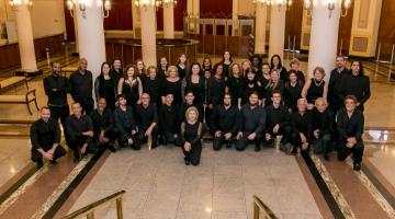 Com 40 integrantes entre homens e mulheres, coral posa para foto em entrada de teatro