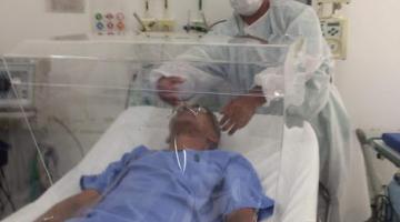 homem deitado em cama de hospital com o cubo plástico em volta #paratodosverem 