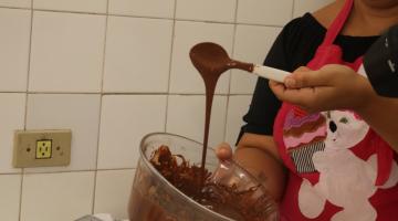 mão mexe em calda de chocolate dentro de vasilha. #paratodosverem