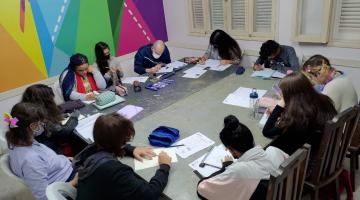 jovens estão sentados à mesa. todos desenham. #paratodosverem 