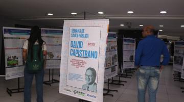 pessoas olhando murais com informações de david capistrano #paratodosverem