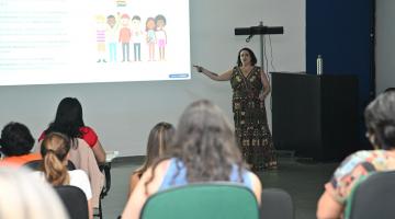 mulher fala para pessoas no auditório #paratodosverem