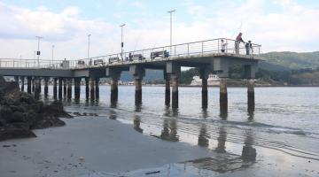 O deck do pescador visto de longe com a maré baixa. #paratodosverem