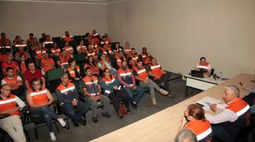 Representantes dos órgãos de Defesa Civil sentados durante treinamento em auditório. #paratodosverem