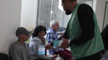 agente entrega material educativo a senhora #paratodosverem
