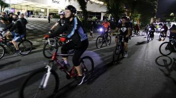 ciclistas estão pedalando pela rua à noite. #paratodosverem