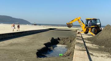 Retroescavadeira retira areia de canal no trecho de praia. #pracegover