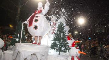 carro alegórico com personagem de boneco de neve. Há 'neve' flutuando no ambiente. #paratodosverem 