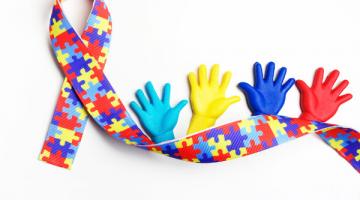 laço do autismo com quatro mãozinhas coloridas ao lado direito. #paratodosverem