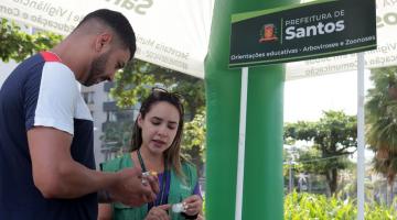 mulher orienta homem em estande educativo #paratodosverem 