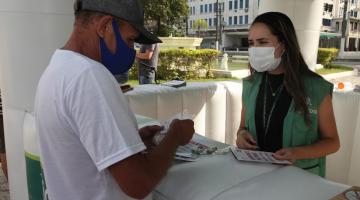 Munícipe recebe sachê de sal grosso e panfletos em tenda montada no Gonzaga. #pracegover