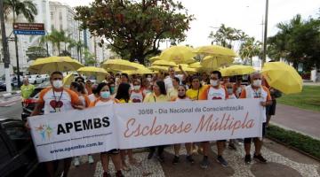 pessoas na caminhada com faixa e guarda chuvas amarelos #paratodosverem