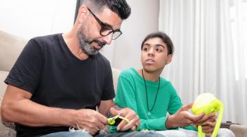 Almir crochetando ao lado do filho Eduardo. #pracegover