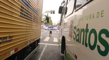 faixa contra o aedes ao fundo, vista entre caminhão e ônibus. #paratodosverem