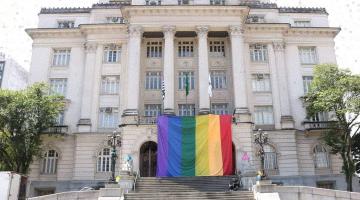 Fachada da Prefeitura com grande bandeira do Orgulho LGBTQIA+ #Paratodosverem