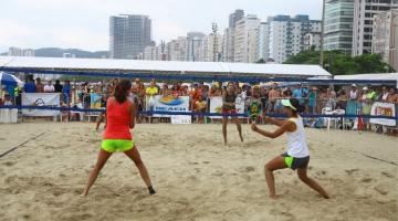 duas pessoas de costas , de frente para uma rede de esportes, em uma praia #paratodosverem