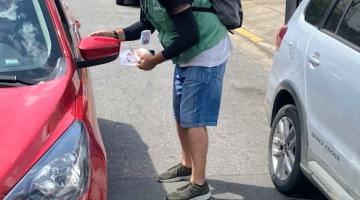 agente entrega panfleto a pessoa em carro #paratodosverem