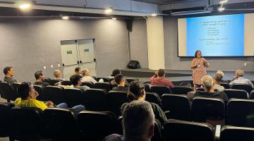 pessoas sentadas em auditório assistem palestra. #paratodosverem 