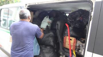 homem está enchendo van com sacos cheios de roupas. O veículo está lotado. #paratodosverem