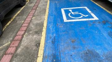 Vaga para estacionamento de veículos de pessoas com deficiências e pessoas ao fundo. #paratodosverem
