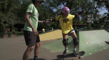 instrutor de skate dá apoio a alluna em pista. #paratodosverem 