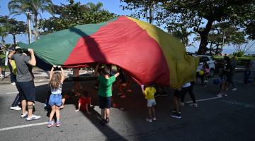 crianças brincando com lona colorida #paratodosverem
